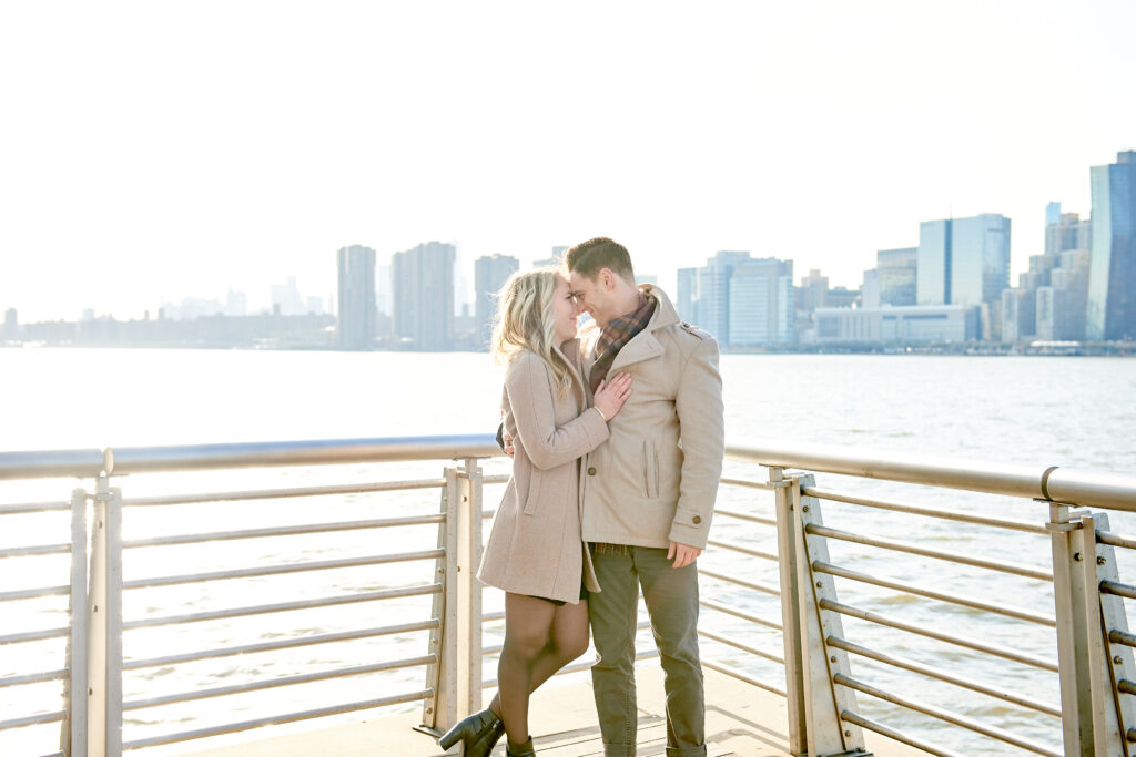 Couple Stands together snuggling noses happily smiling after a successful proposal in Gantry Plaza Park, in Long Island City Queens New York - Corey Lamar Photography
