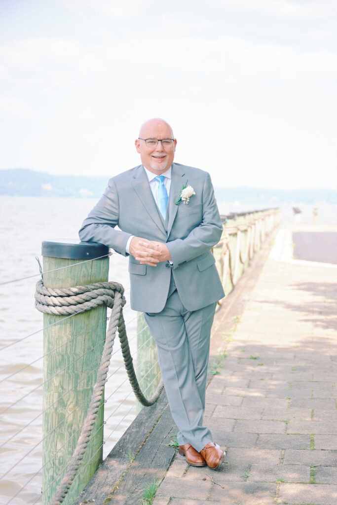 Groom Poses on a beam near the Hudson River behind him.  Hudson Valley Wedding