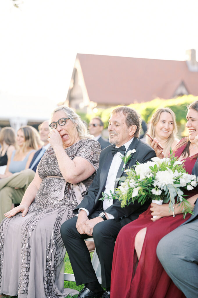 Parents joyfully look onto wedding ceremony with tears, at the Saint Clements Castle.