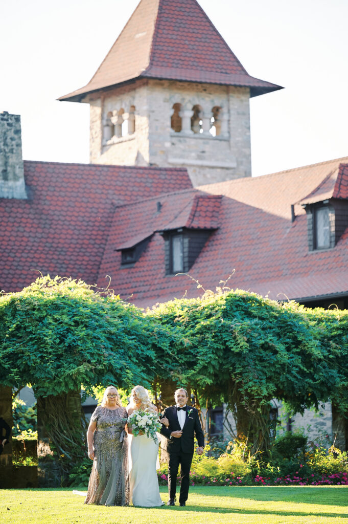 Bride along with her parents walk to Ceremony location in the Saint Clements Castle Gardens.  Photo taken by NYC Wedding Photographer Corey Lamar Photography