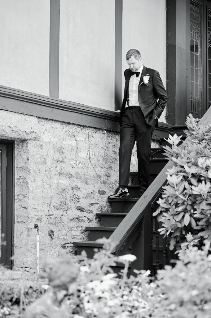 Groom walking down stairs of Saint Clements Castle balcony.  Photo is in black and white for artistic effect, taken by Corey Lamar Photography, New York City Wedding Photographer