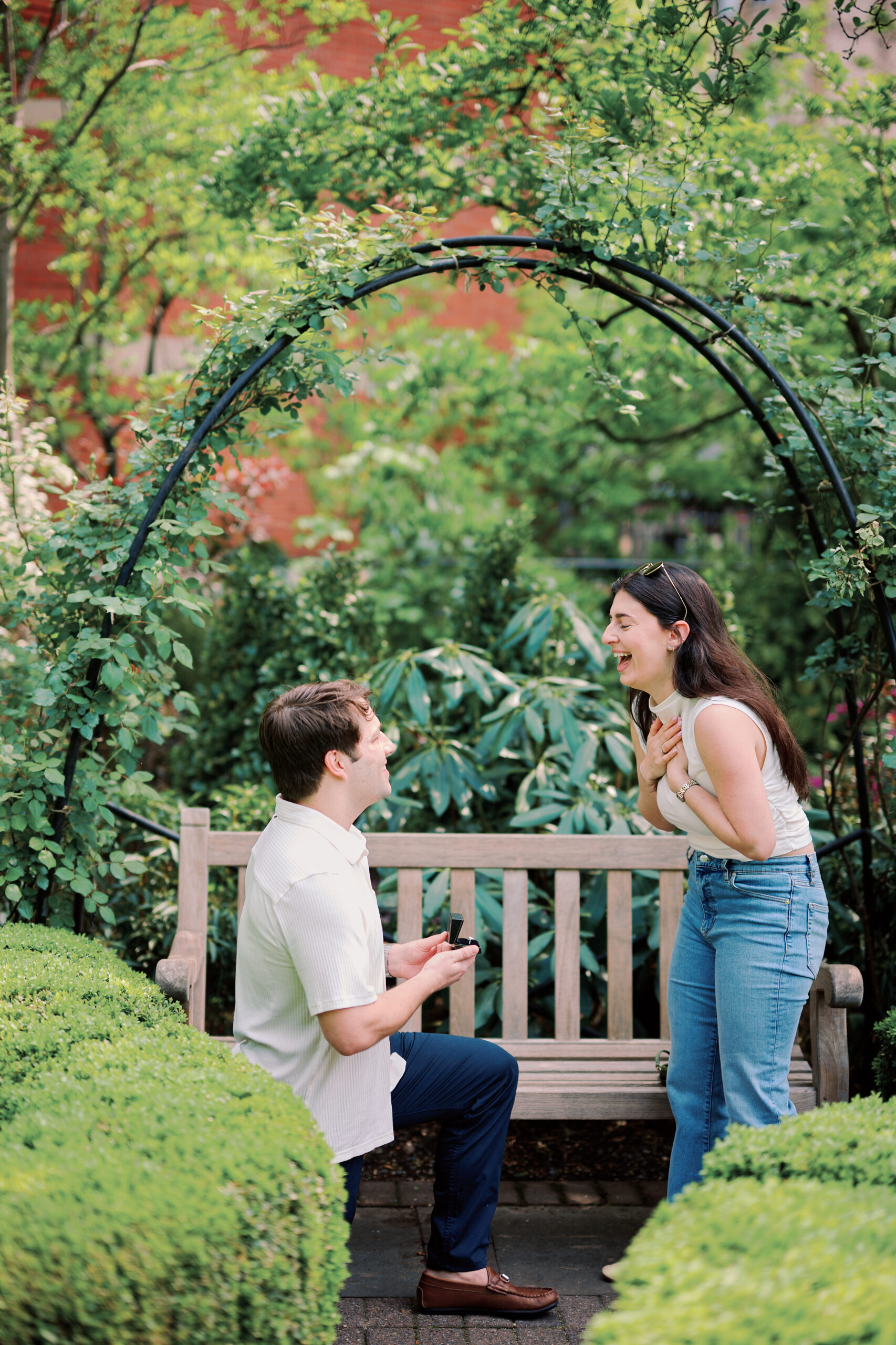 Mark kneeling in Jefferson Market Garden proposing to Vanessa during a West Village engagement photos session