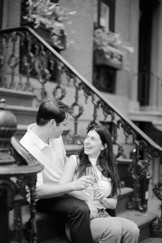 Mark and Vanessa toasting with champagne flutes on a West Village brownstone stoop