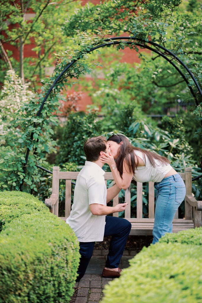 Mark and Vanessa kissing after proposal during West Village engagement photos at Jefferson Market Garden