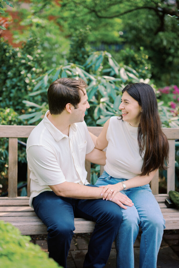 Couple sharing a laugh amid garden hedges during West Village engagement photos session