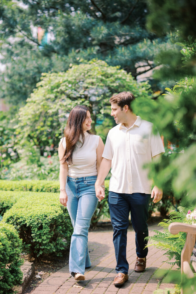 Mark and Vanessa walking hand in hand during West Village engagement photos at Jefferson Market Garden